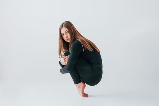 Taking a break. Young woman in sportive clothes doing gymnastics indoors.