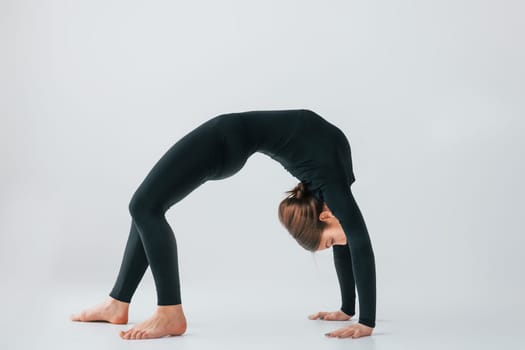 Difficult exercises. Young woman in sportive clothes doing gymnastics indoors.