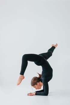 Difficult exercises. Young woman in sportive clothes doing gymnastics indoors.