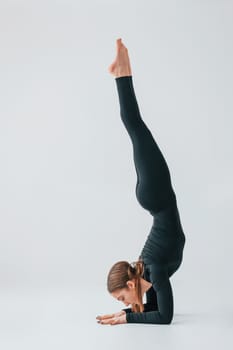 Difficult exercises. Young woman in sportive clothes doing gymnastics indoors.