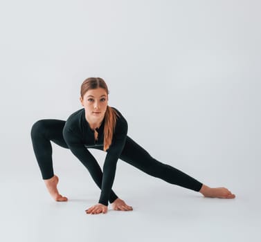 Slim body type. Young woman in sportive clothes doing gymnastics indoors.