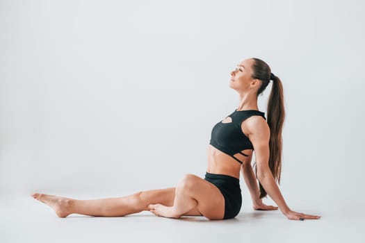 Slim body type. Young woman in sportive clothes doing gymnastics indoors.
