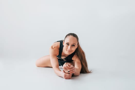 Focused on the exercises. Young woman in sportive clothes doing gymnastics indoors.