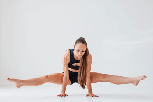 Standing on the hands. Young woman in sportive clothes doing gymnastics indoors.