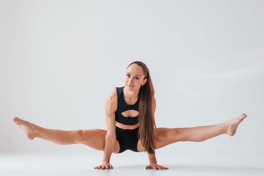 Standing on the hands. Young woman in sportive clothes doing gymnastics indoors.