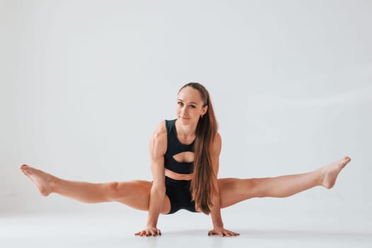 Standing on the hands. Young woman in sportive clothes doing gymnastics indoors.