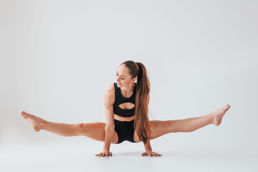 Beautiful body. Young woman in sportive clothes doing gymnastics indoors.