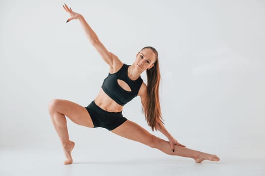 Exercises for stretch and strength. Young woman in sportive clothes doing gymnastics indoors.