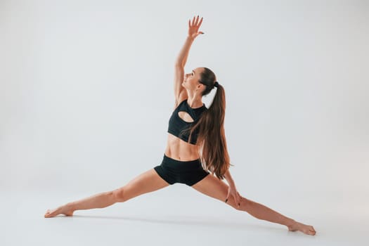 Strong legs. Young woman in sportive clothes doing gymnastics indoors.