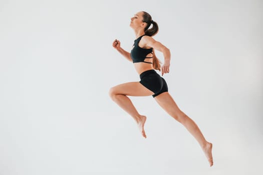 Flexibility of the body. Young woman in sportive clothes doing gymnastics indoors.