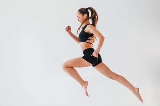 Flexibility of the body. Young woman in sportive clothes doing gymnastics indoors.