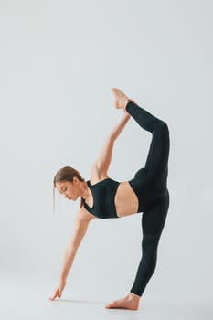 Conception of active lifestyle. Young woman in sportive clothes doing gymnastics indoors.