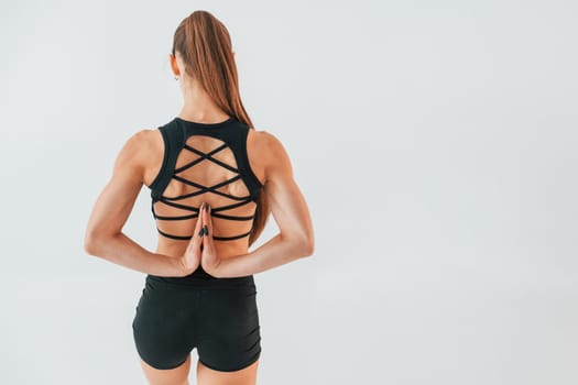Conception of active lifestyle. Young woman in sportive clothes doing gymnastics indoors.