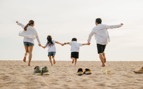 Father, mother and kids take off shoes run on sand beach, Back view of family parents with children fun holding hands together running to beach in holiday, Travel, active lifestyle, Happy family day
