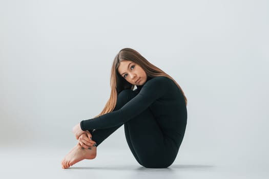 Conception of energy. Young woman in sportive clothes doing gymnastics indoors.