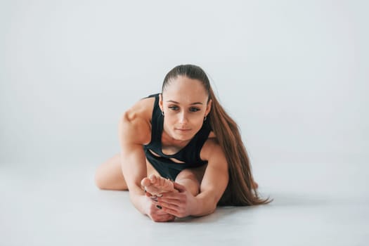 Professional trainer. Young woman in sportive clothes doing gymnastics indoors.