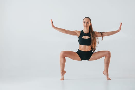 Young woman in sportive clothes doing gymnastics indoors.