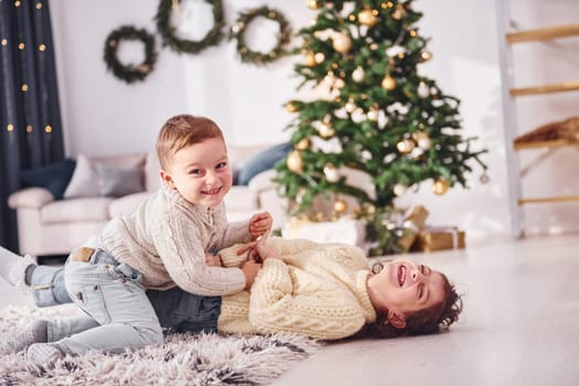 Laying down and playing. Little brother and sister is at christmas decorated room together.