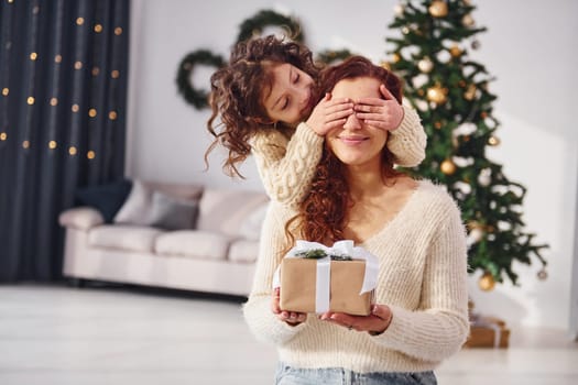 Making surprise. Mother with her little daughter is at home. Christmas decorations.