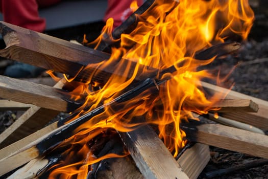 A fire burns in a campfire with a red fire in the background. High quality photo