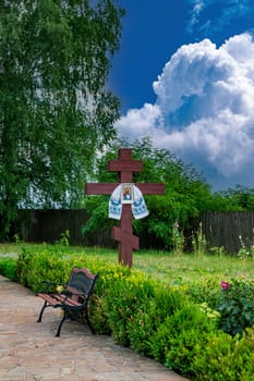 Christian cross with an icon against a blue sky with clouds. Christian cross. Easter decoration. Religion and culture. Orthodoxy, Catholicism, Protestantism. Ukrainian Orthodox Church.