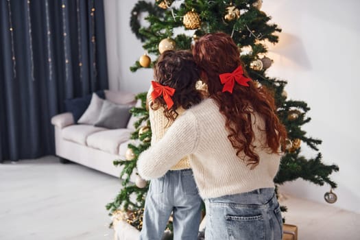 Decorating tree. Mother with her little daughter is at home.