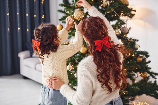 Decorating tree. Mother with her little daughter is at home.