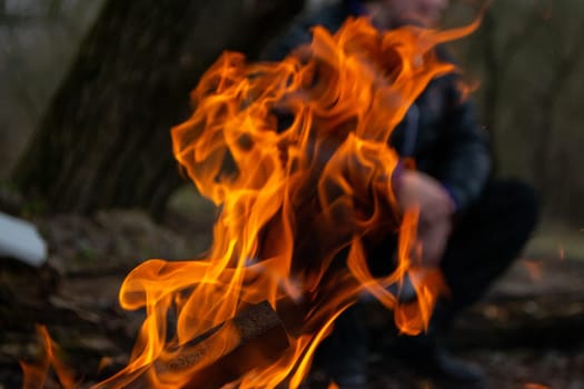 A fire burns in a campfire with a red fire in the background. High quality photo