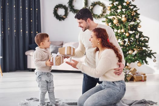 Giving present to the boy. Father and mother with son is at home celebrating new year together.