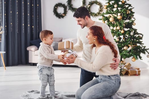 Giving present to the boy. Father and mother with son is at home celebrating new year together.