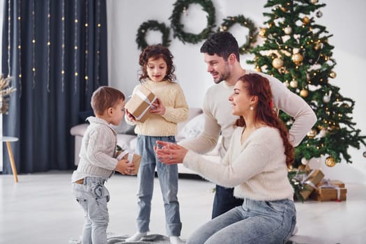 With gift boxes. Family celebrating new year with their children at home.