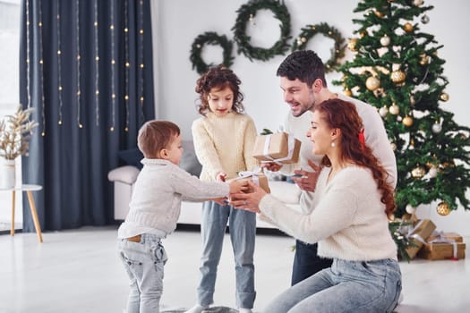 With gift boxes. Family celebrating new year with their children at home.