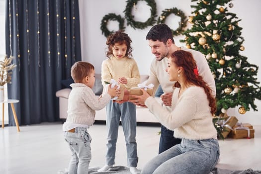 With gift boxes. Family celebrating new year with their children at home.