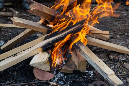 A fire burns in a campfire with a red fire in the background. High quality photo