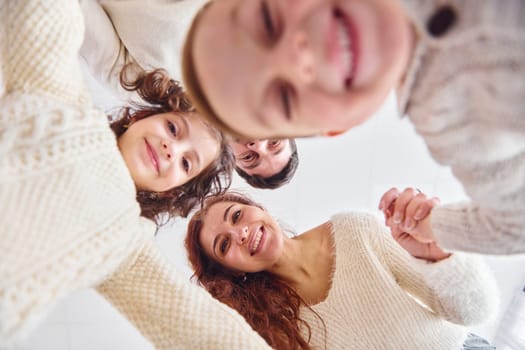Smiling and having fun. View from below. Happy family looking down.