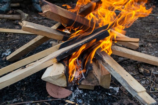 A fire burns in a campfire with a red fire in the background. High quality photo