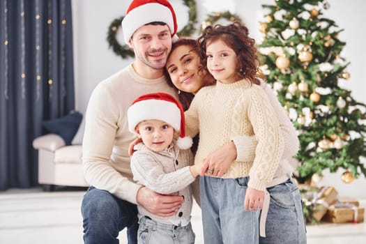 In christmas hats. Family celebrating new year with their children at home.