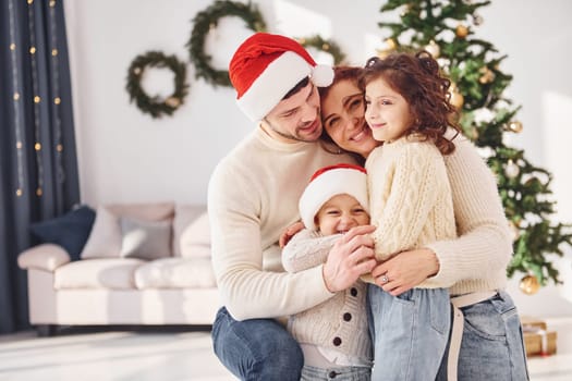 In christmas hats. Family celebrating new year with their children at home.