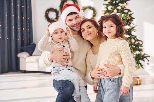 In christmas hats. Family celebrating new year with their children at home.