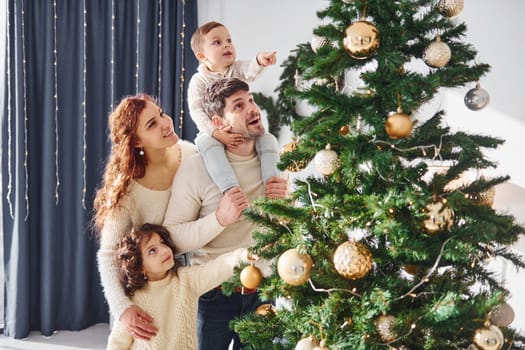 Decorating christmas tree. Family celebrating new year with their children at home.