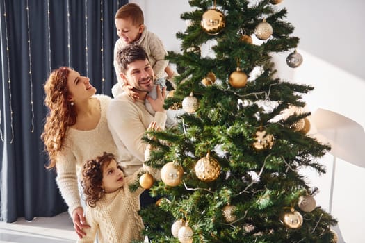 Decorating christmas tree. Family celebrating new year with their children at home.