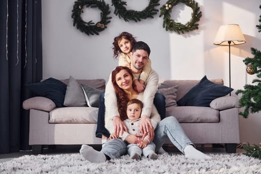 Sitting near sofa. Family celebrating new year with their children at home.