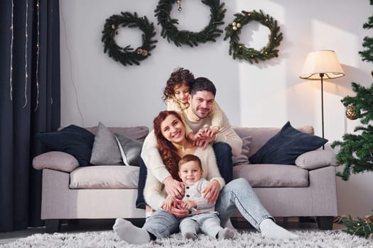 Sitting near sofa. Family celebrating new year with their children at home.