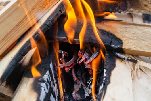 A fire burns in a campfire with a red fire in the background. High quality photo