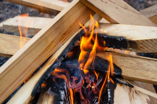 A fire burns in a campfire with a red fire in the background. High quality photo