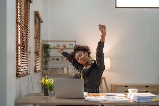 Black business woman stretches in office at workplace.