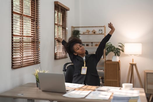 Black business woman stretches in office at workplace.