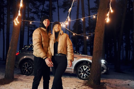 Holding by the hands. Couple standing in the forest and celebrating New year.