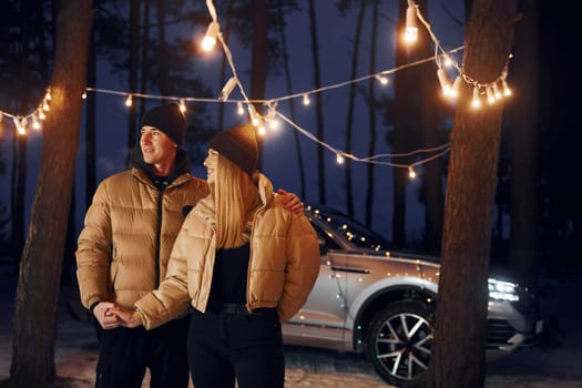 Holding by the hands. Couple standing in the forest and celebrating New year.