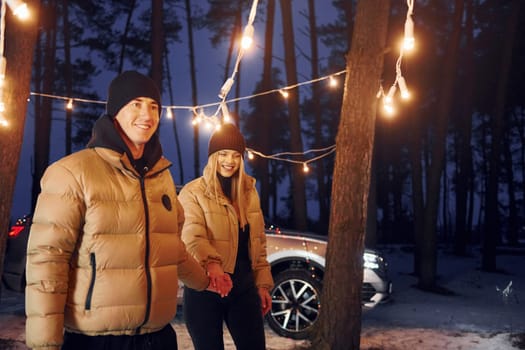 Holding by the hands. Couple standing in the forest and celebrating New year.